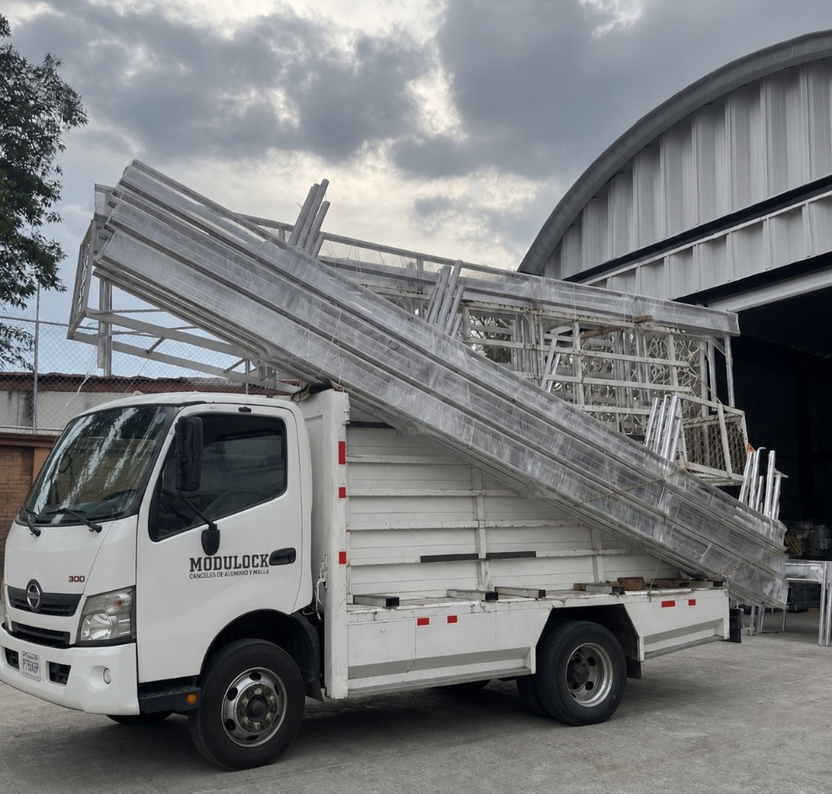 Flota de transporte de CAAMODULOCK cargada con canceles de aluminio y perfiles metálicos